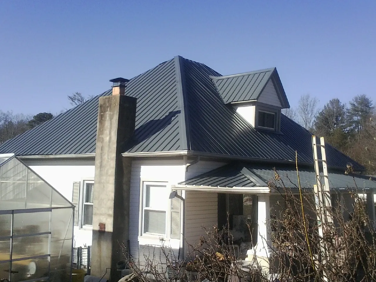 Dark blue standing seam metal roof on a white farmhouse with dormer — Slate & Tile Roof Repair by Roofing Brothers in New Stuyahok
