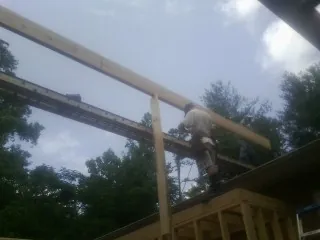 Carpenter setting a ridge beam over a new addition frame — Ice Dam Removal by Roofing Brothers in New Stuyahok