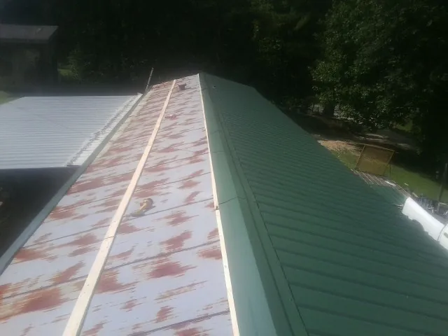 Old rusted panels beside newly installed green metal roofing — Wind Damage Roof Repair by Roofing Brothers in New Stuyahok