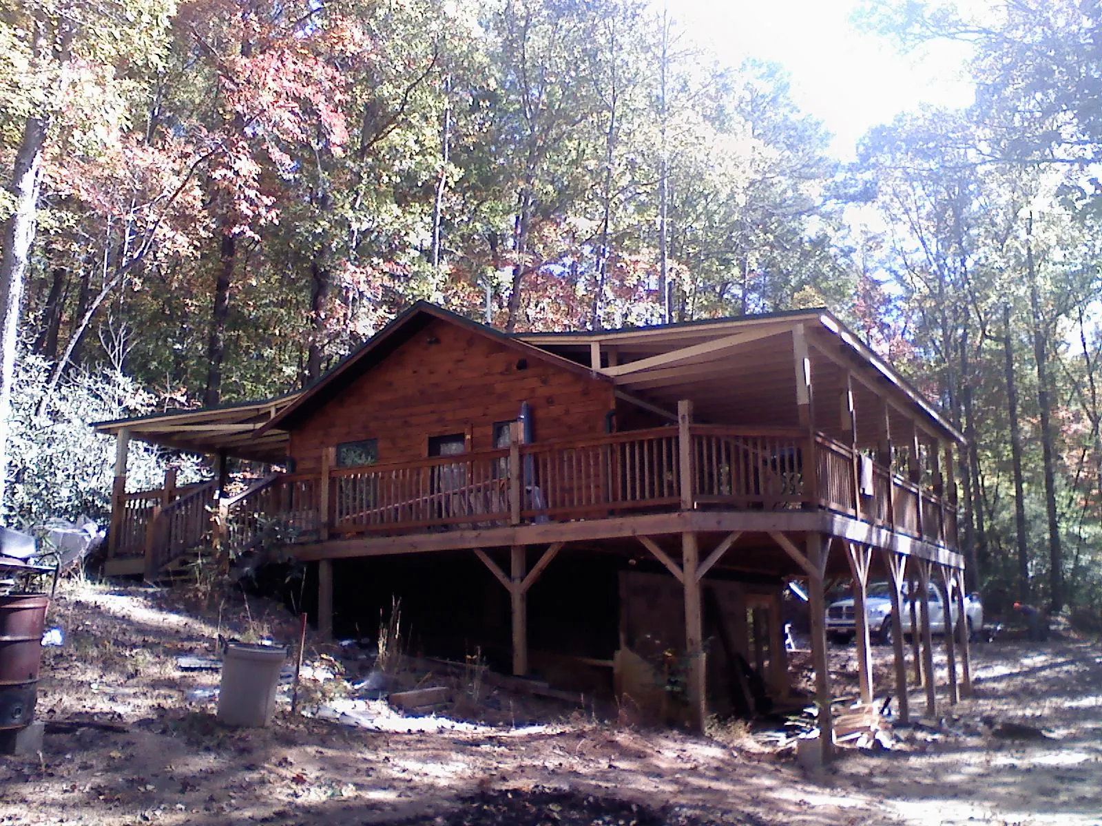 Log cabin with a wraparound porch and metal roof in the fall in New Stuyahok