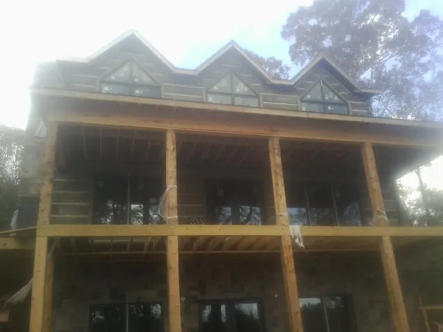 Dormers and porch framing on a large log home under construction — Roof Coating work by our crew in New Stuyahok