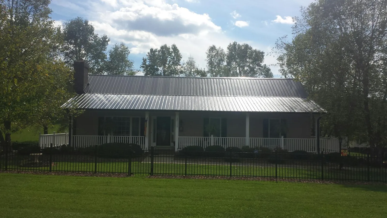 Gray metal roof on a brick ranch with a full width front porch — Gutter Guard Installation work by our crew in New Stuyahok