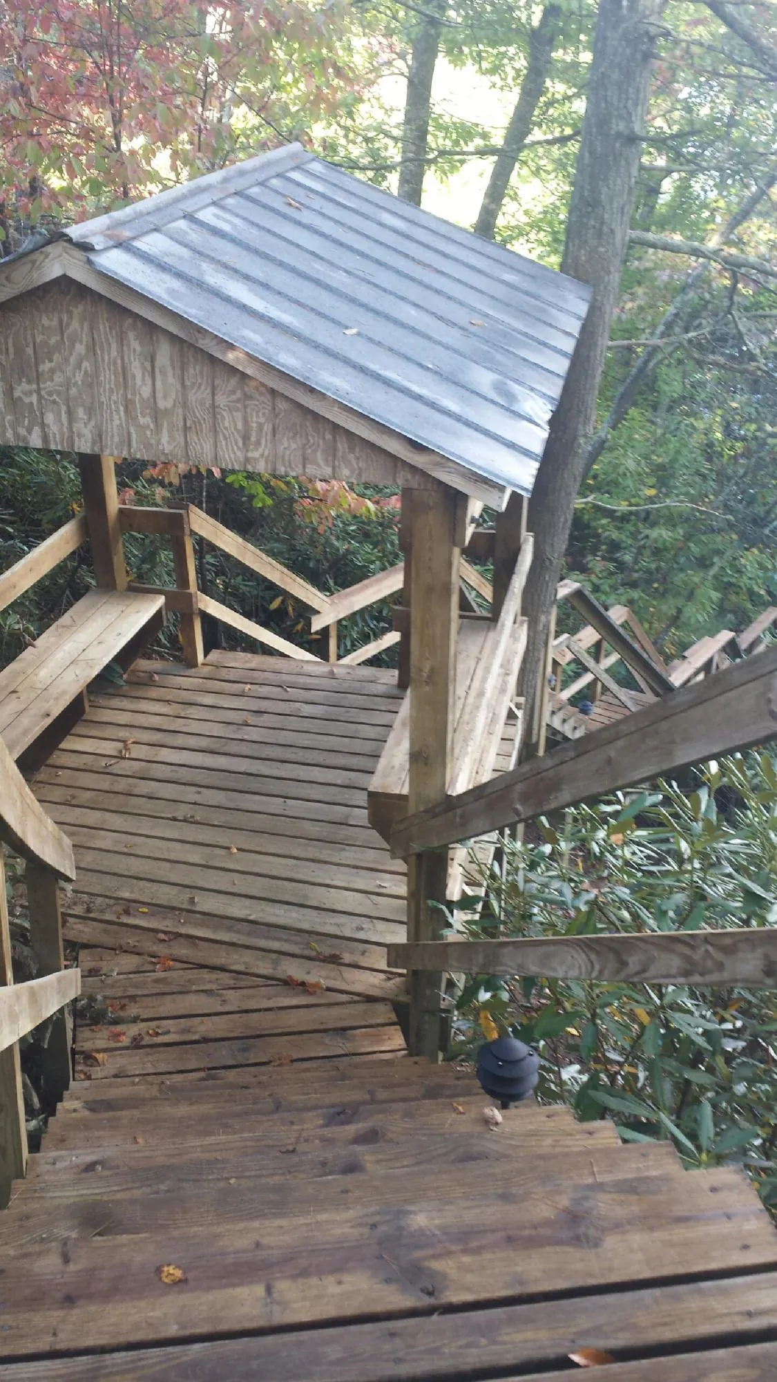 Metal roofed shelter over wooden steps on a wooded walkway — Skylight Repair & Installation work by our crew in New Stuyahok